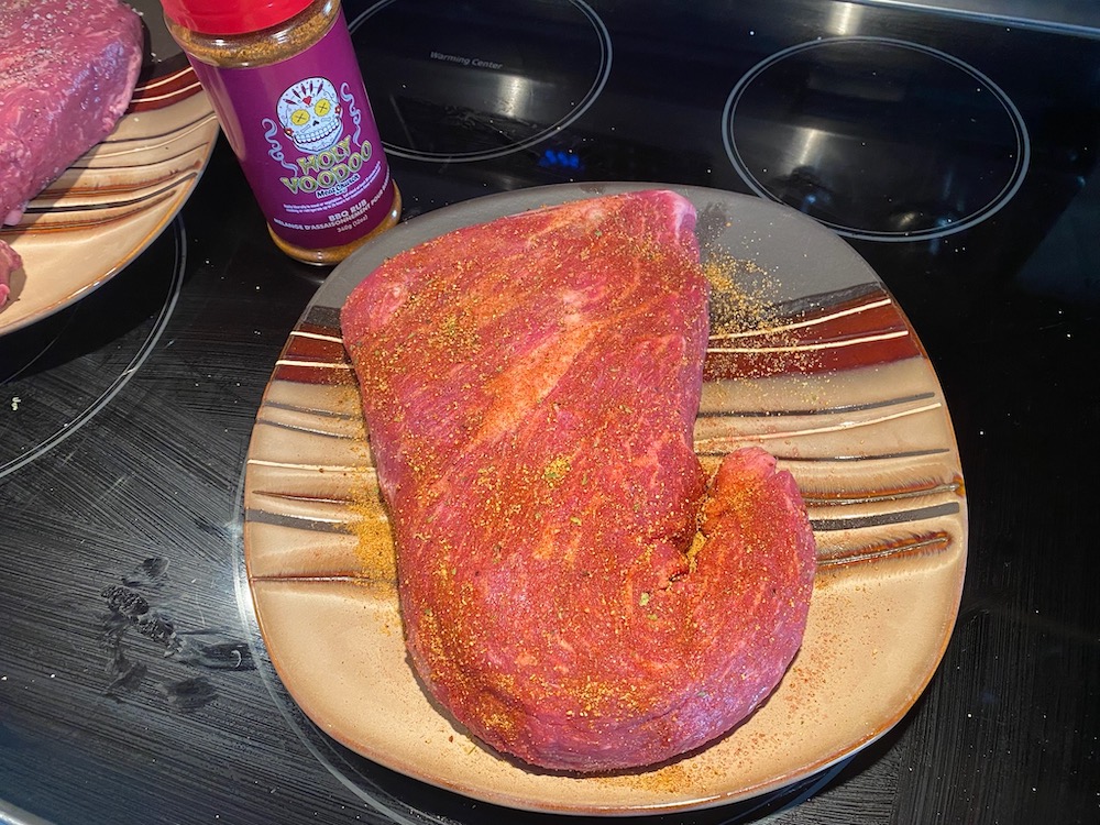 Seasoning the meat with Meat Church's Holy Voodoo BBQ Rub